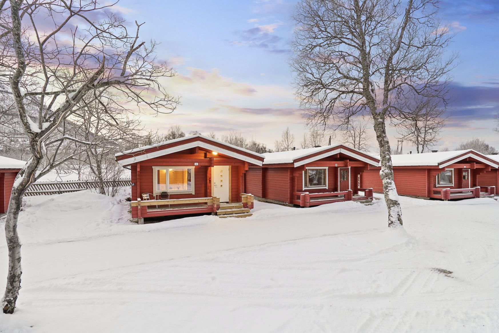 Row of traditional red wooden cabins in Tromsø, Norway, surrounded by snow